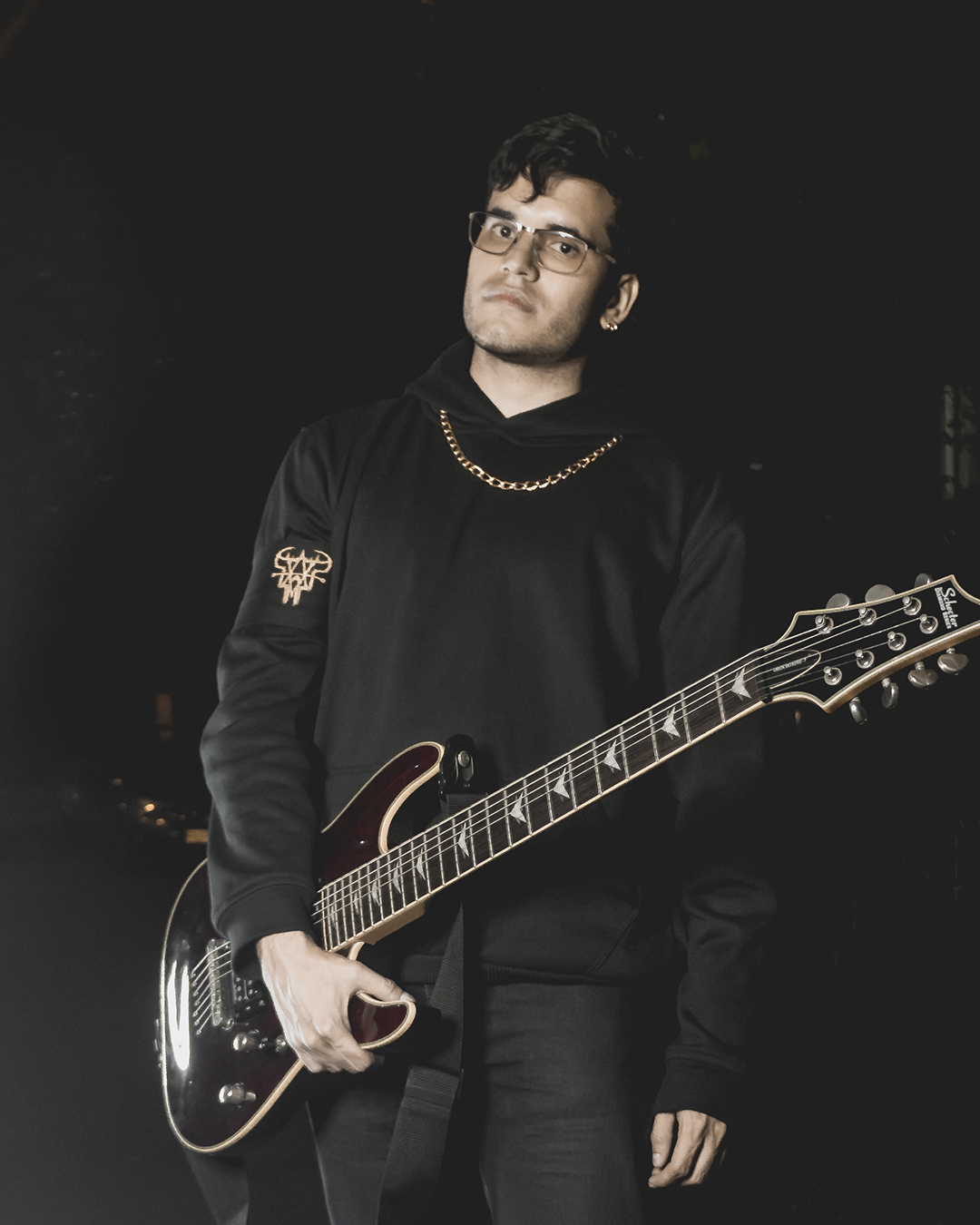 Foto de guitarrista de la banda ground of chaos sostienendo una guitarra en la noche con ropa negra