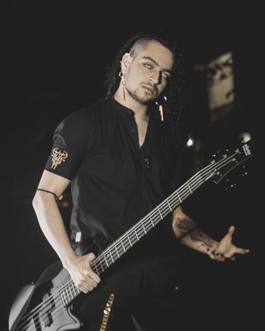 Foto de bajista de la banda ground of chaos sostienendo un bajo en la noche con ropa negra